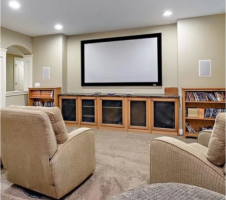 Cozy home entertainment area with projector screen and built in cabinets and shelves.