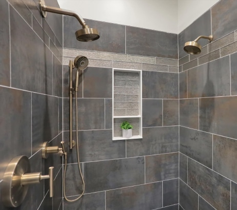 Sleek walk in shower remodel with slate tile, cutouts and multiple shower heads.